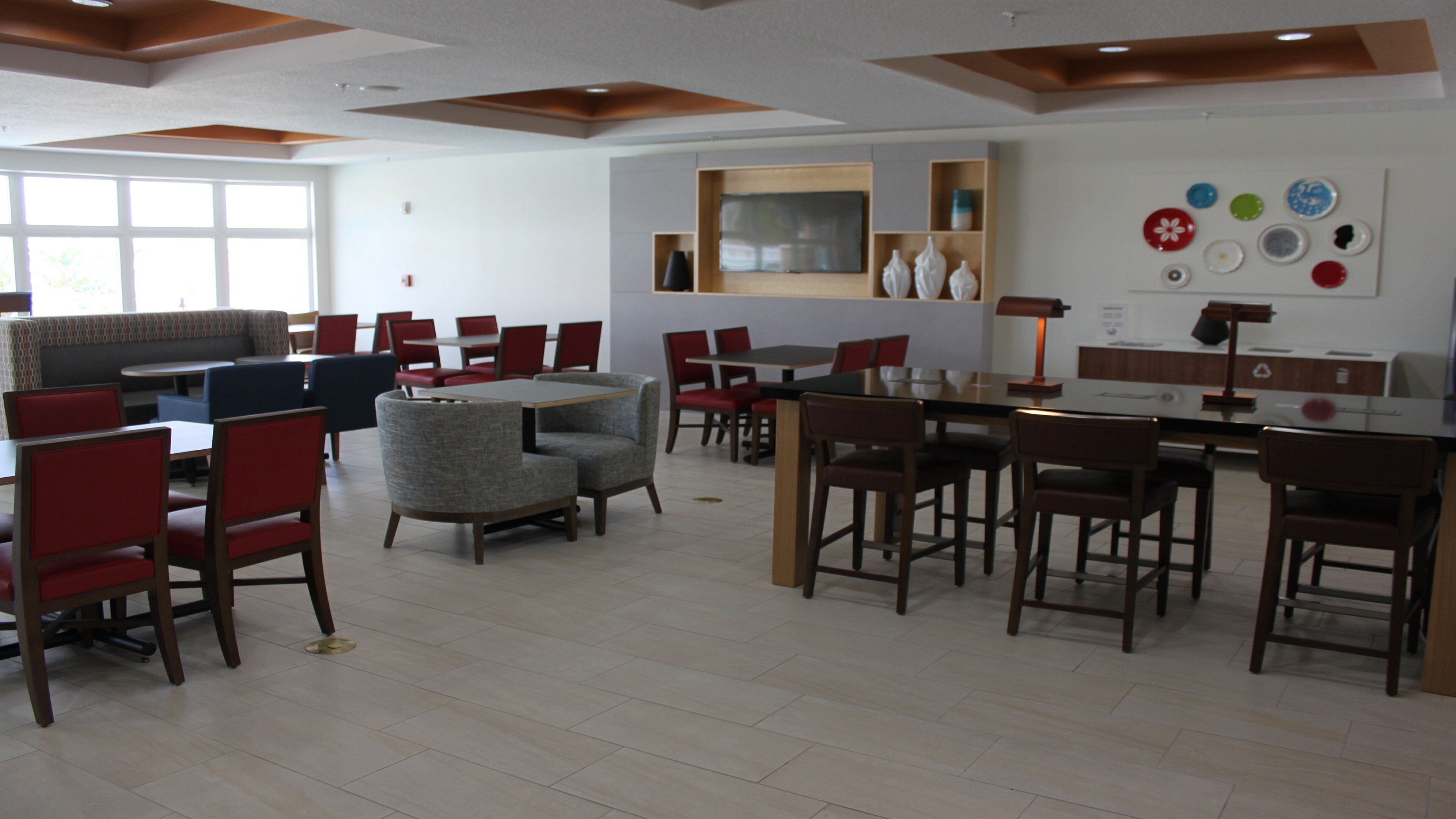 Uma sala de jantar moderna com cadeiras vermelhas e cinzentas, uma mesa redonda e um sofá.