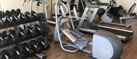 A gym with various exercise equipment including treadmills, elliptical machines, and dumbbells.