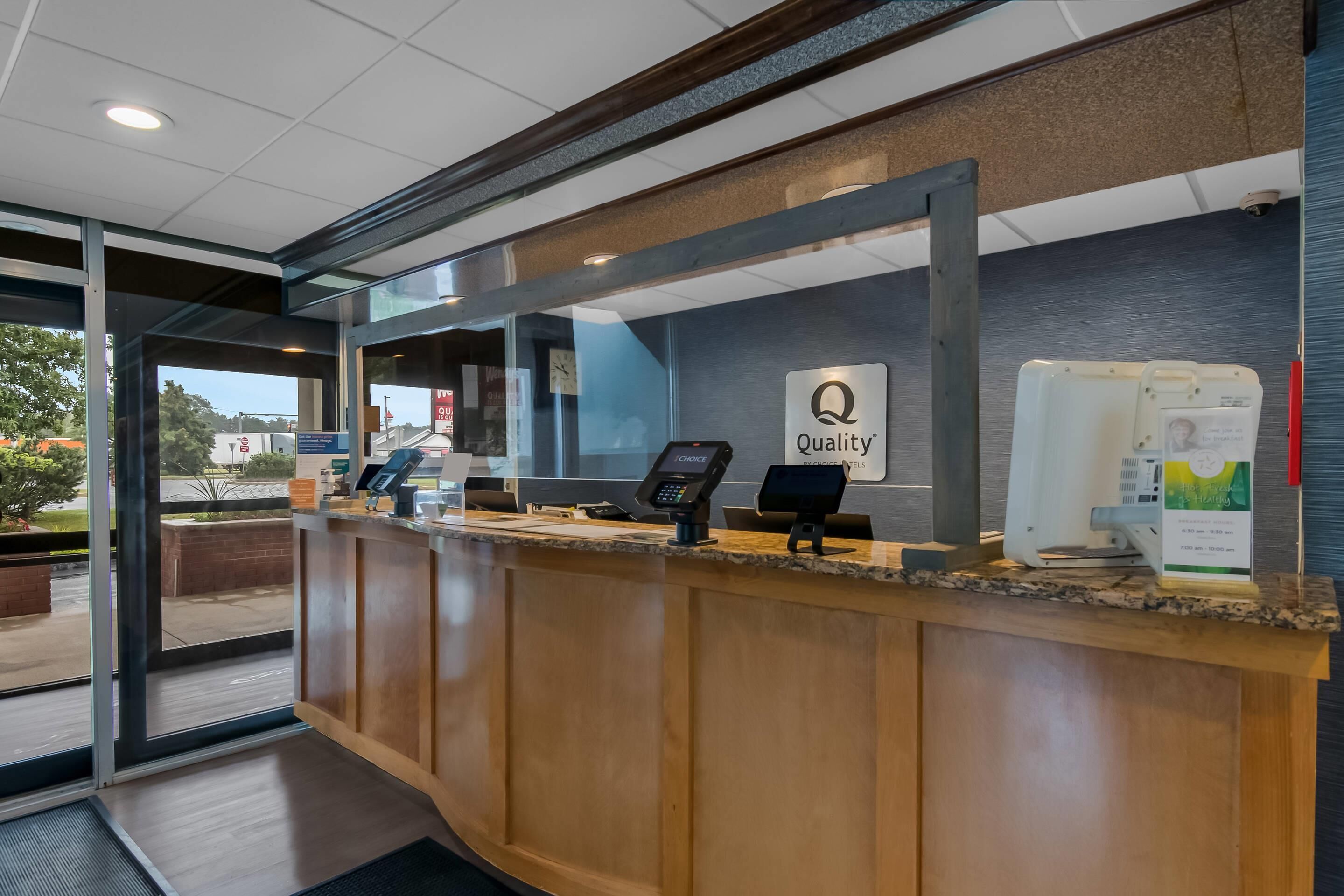A reception area with a wooden counter, a glass door, and a sign that reads "Quality."