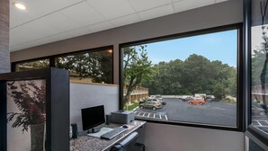 A modern office space with a large window overlooking a parking lot and trees.