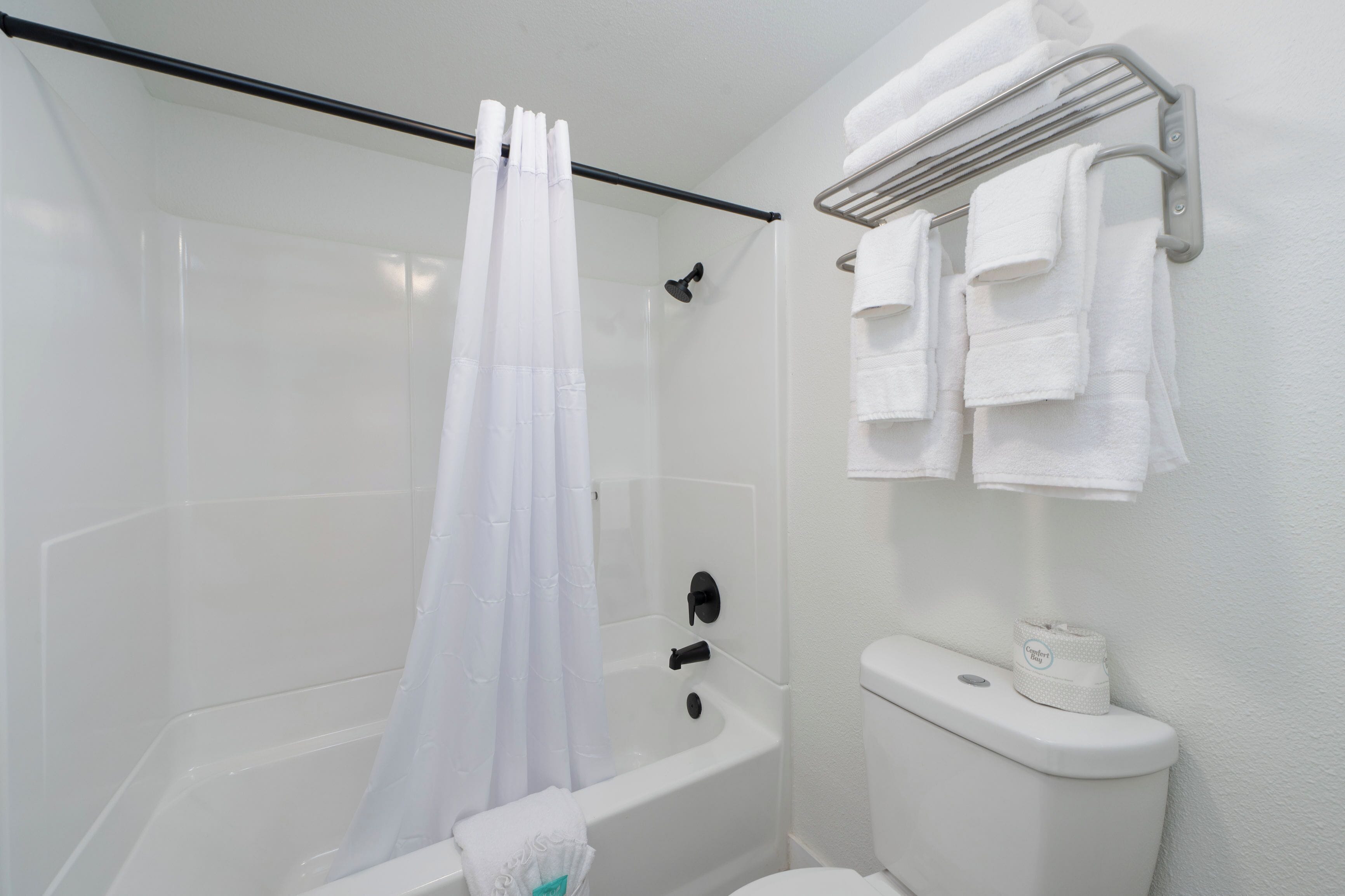 Un baño con ducha, inodoro y toallero.