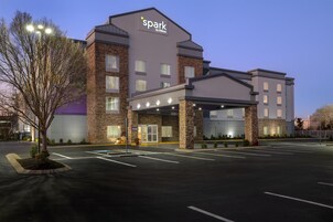 Un hotel de diseño moderno, con un llamativo letrero 'spark by Hilton', una entrada cubierta y un estacionamiento.
