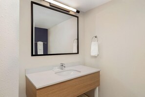Une salle de bain moderne avec un lavabo blanc, un grand miroir et un porte-serviettes.