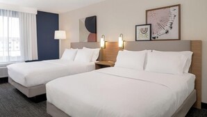 A hotel room with two beds, a large window with curtains, a wall-mounted artwork, and a nightstand with a lamp. - Spark by Hilton Murfreesboro (Murfreesboro)