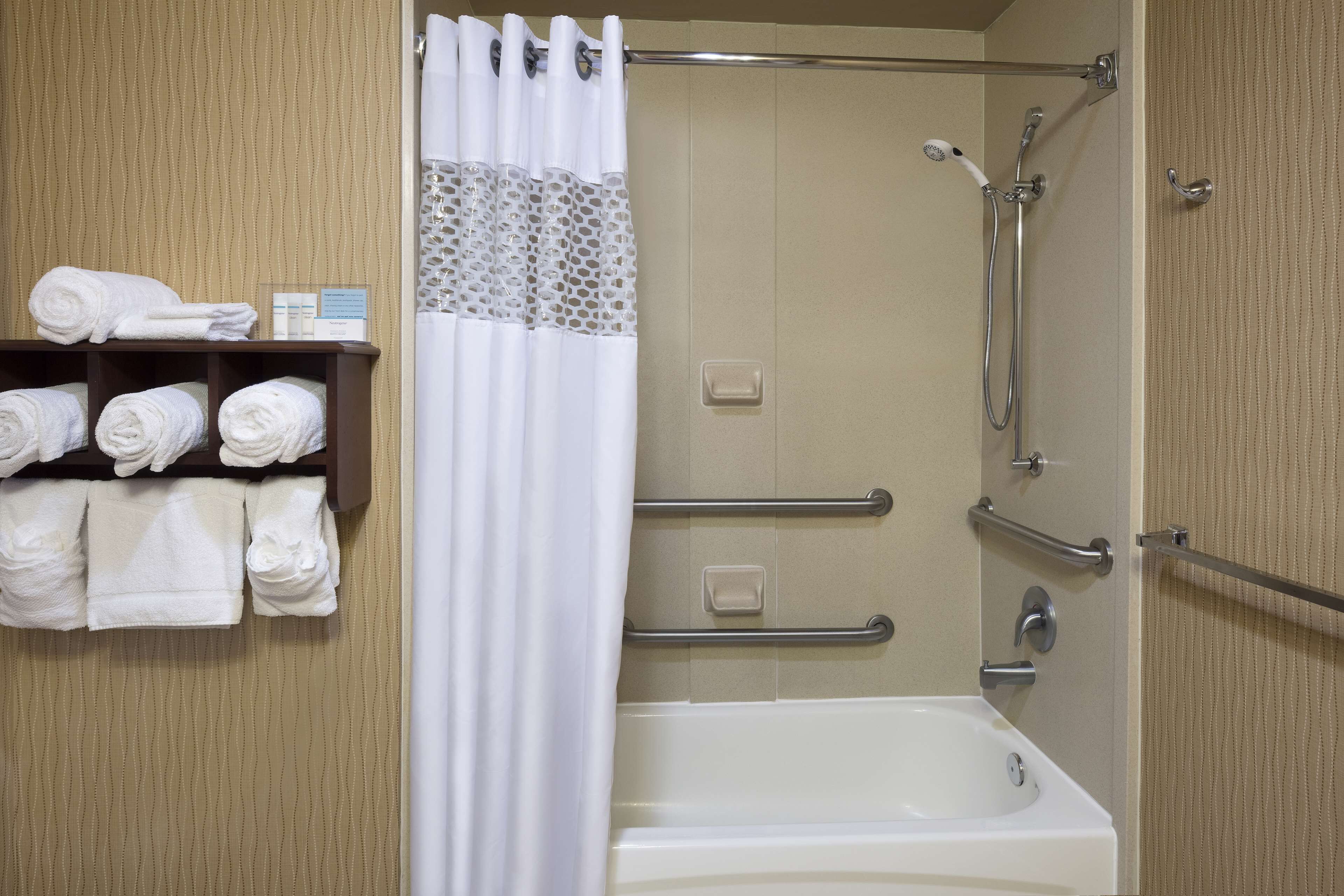 A bathroom with a bathtub, shower, and towel rack with towels.