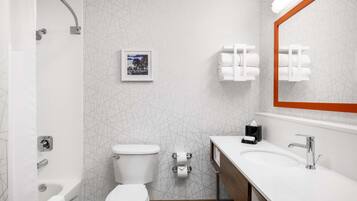 A modern bathroom with a shower, toilet, sink, and a mirror with an orange frame.