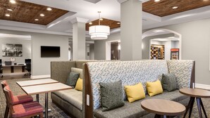 Un moderno vestíbulo de hotel con un sofá modular, una mesa pequeña y una mesa redonda.