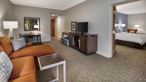 Una habitación de hotel con sofá, televisor, escritorio y cama.