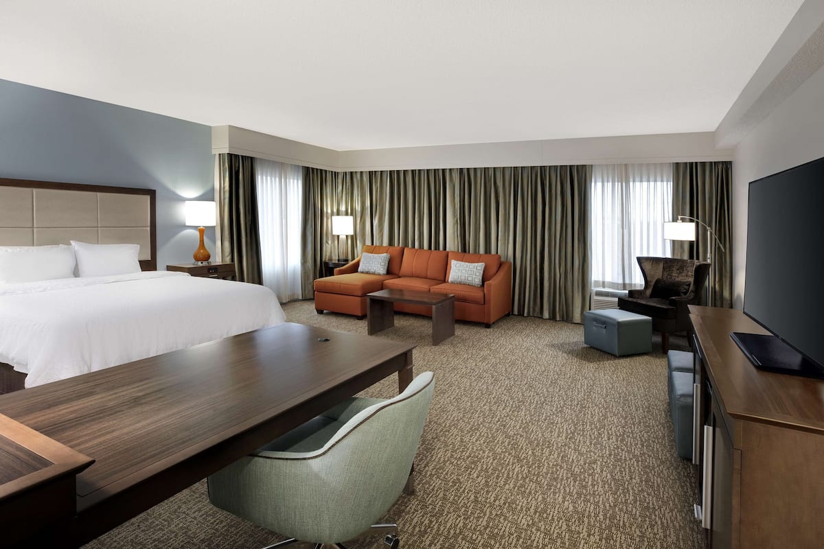 Une chambre d’hôtel équipée d’un lit, d’un canapé, d’un bureau, d’une chaise, d’une télévision et d’une lampe.