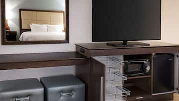 A hotel room with a bed, a TV, a microwave, and a mini-fridge.