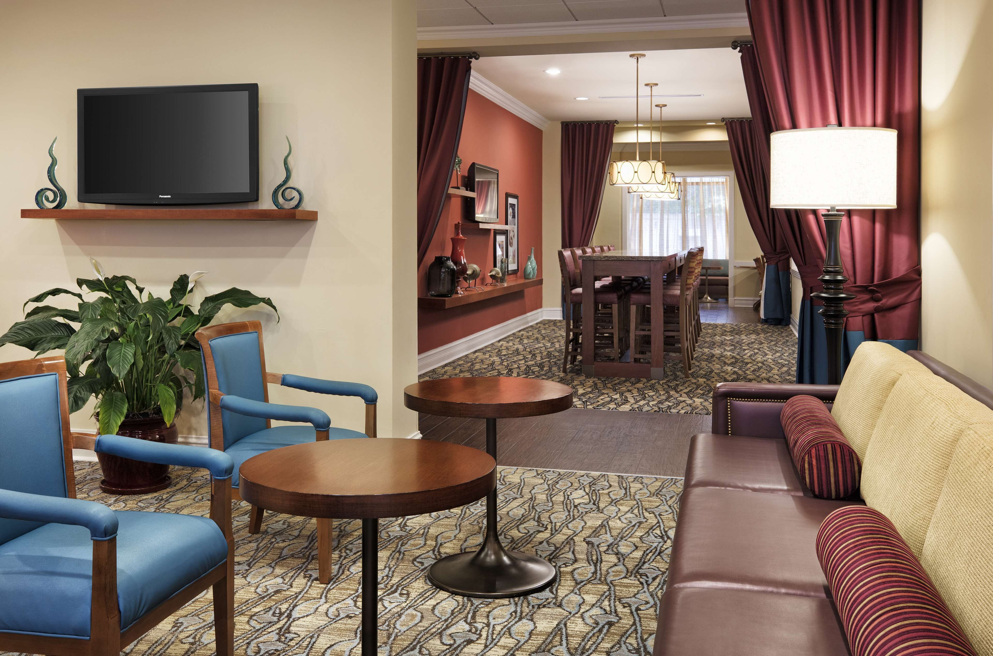 Un vestíbulo de hotel con televisión, zona de estar, mesa de comedor y una araña.
