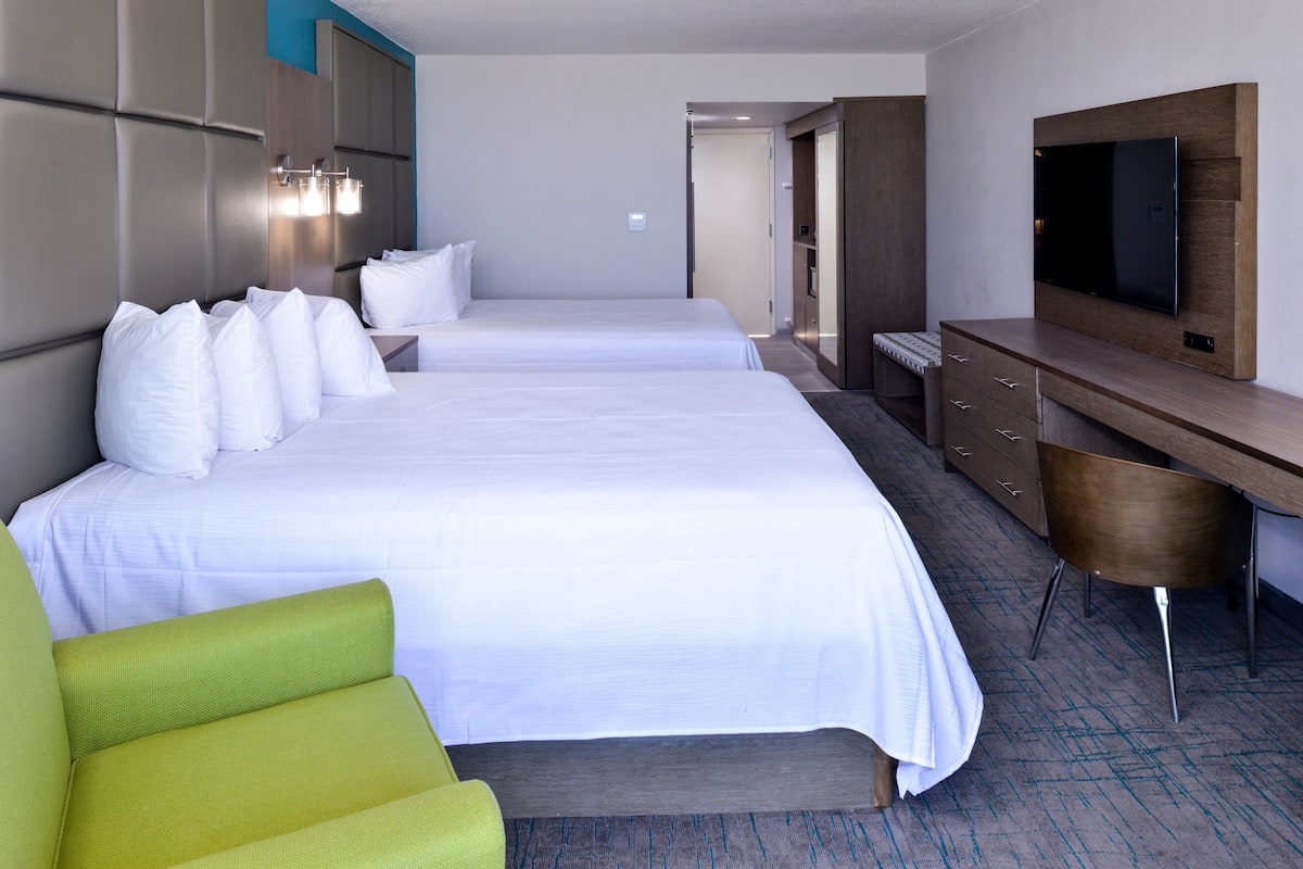 Ett hotellrum med två sängar, ett skrivbord, en tv och en sittgrupp.