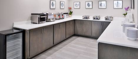 A modern kitchen with a white countertop, stainless steel appliances, and grey cabinets.