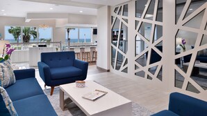 Una sala moderna con un conjunto de sofá azul, una mesa de centro blanca y un separador geométrico de pared.