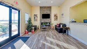 A hotel lobby with a fireplace, seating area, and a reception desk. - OYO Hotel Rosenberg TX I-69 (Rosenberg)