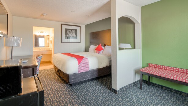 A hotel room with a bed, a desk, a bench, and a mirror. - OYO Hotel Rosenberg TX I-69 (Rosenberg)