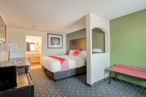 Quarto de hotel com cama, escrivaninha, banco e espelho.