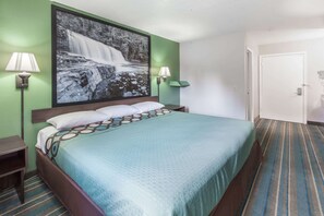 A hotel room with a large bed, two bedside lamps, a green wall, and a door. - Super 8 by Wyndham Chickasha (Chickasha)