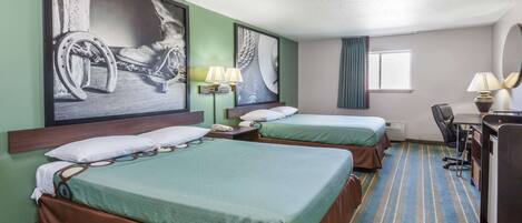 A hotel room with two beds, a desk, a chair, and artwork on the walls.