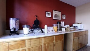 Une cuisine équipée d’une machine à café, d’un appareil à gaufres et de divers autres appareils de cuisine, le tout posé sur le plan de travail.