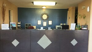 Un comptoir d’accueil avec une horloge, des certificats encadrés et un ordinateur.