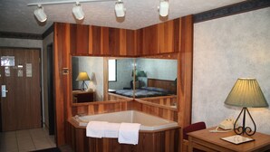 Habitació amb interior de fusta, un gran mirall, una banyera, un escriptori amb una làmpada i una cadira.