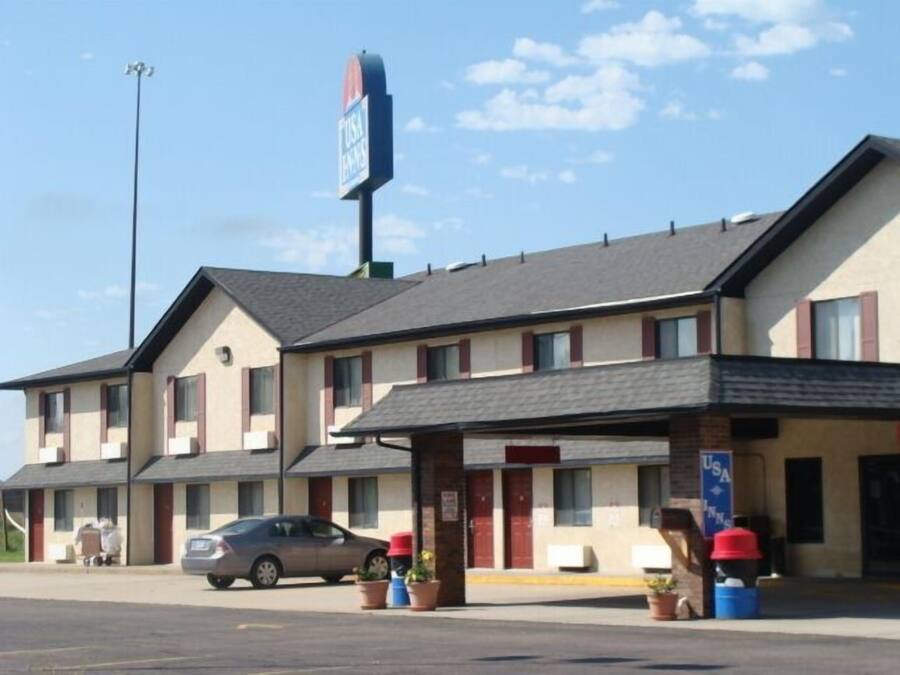 A motel with a two-story structure, a parking lot, and a sign indicating it is a USA Inn.