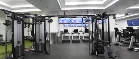 Une salle de sport équipée de divers appareils d’exercice, de tapis de course et de machines de musculation.