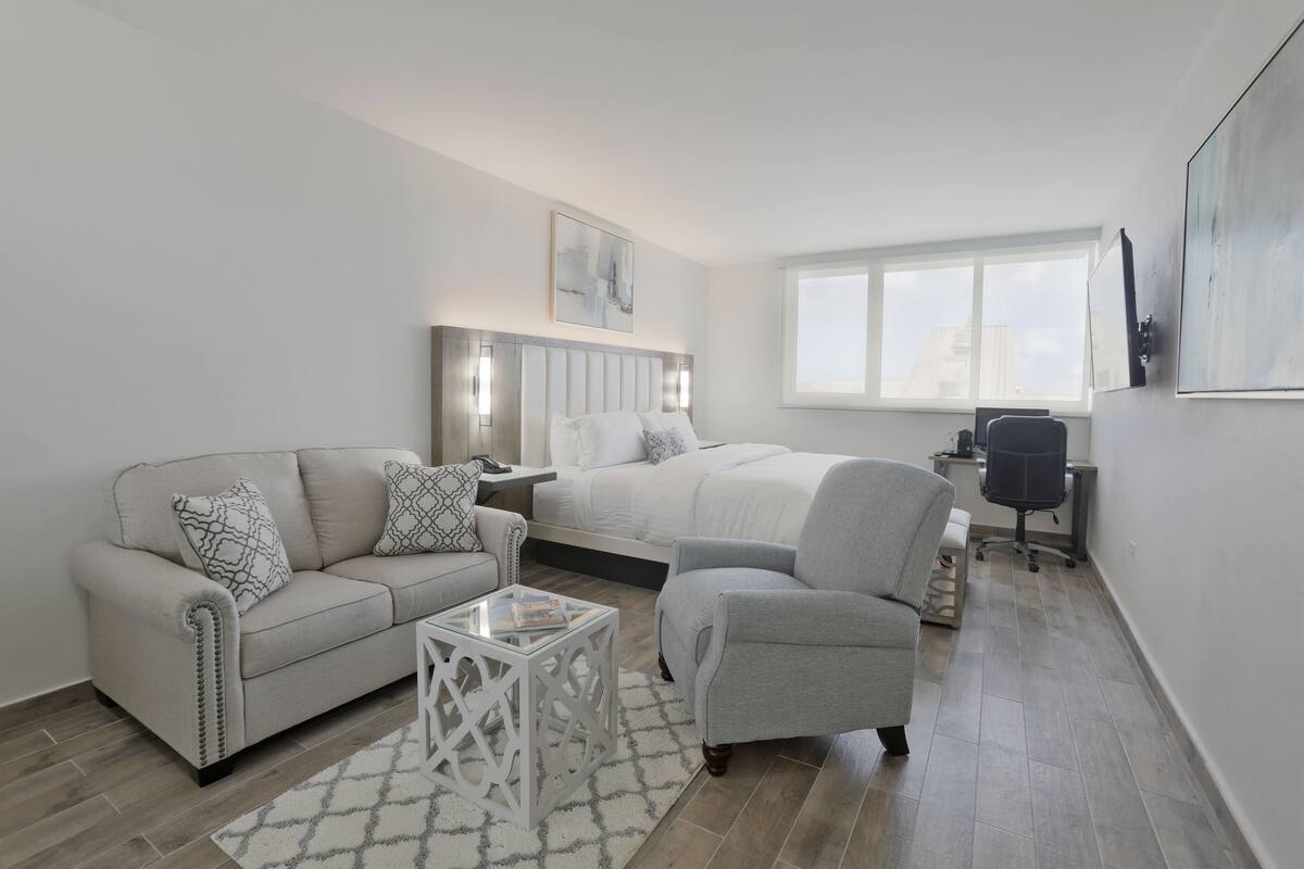 Un dormitorio moderno con cama, sofá, sillón, escritorio y ventana.