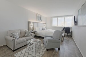 A modern bedroom with a bed, a sofa, a chair, a desk, and a window.
