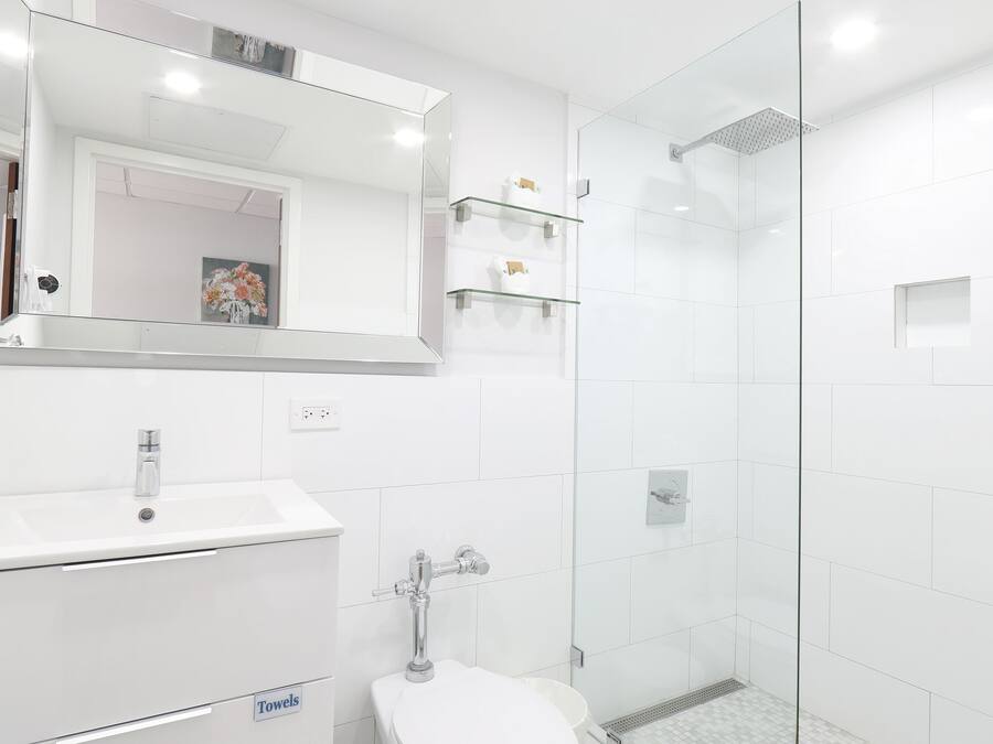 A modern bathroom with a glass shower enclosure, a white sink, and a patterned floor.