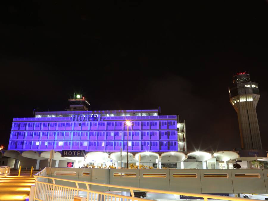 A hotel with a modern design, featuring a prominent 'HOTEL' sign and a large, illuminated structure in the background.