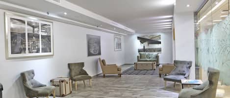 A spacious lobby with a high ceiling, modern furniture, and artwork on the walls.
