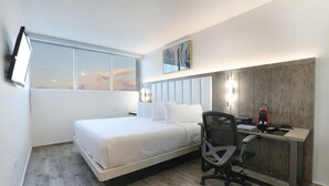 Une chambre à coucher moderne, équipée d’un lit, d’un bureau, d’une chaise et d’une grande fenêtre.
