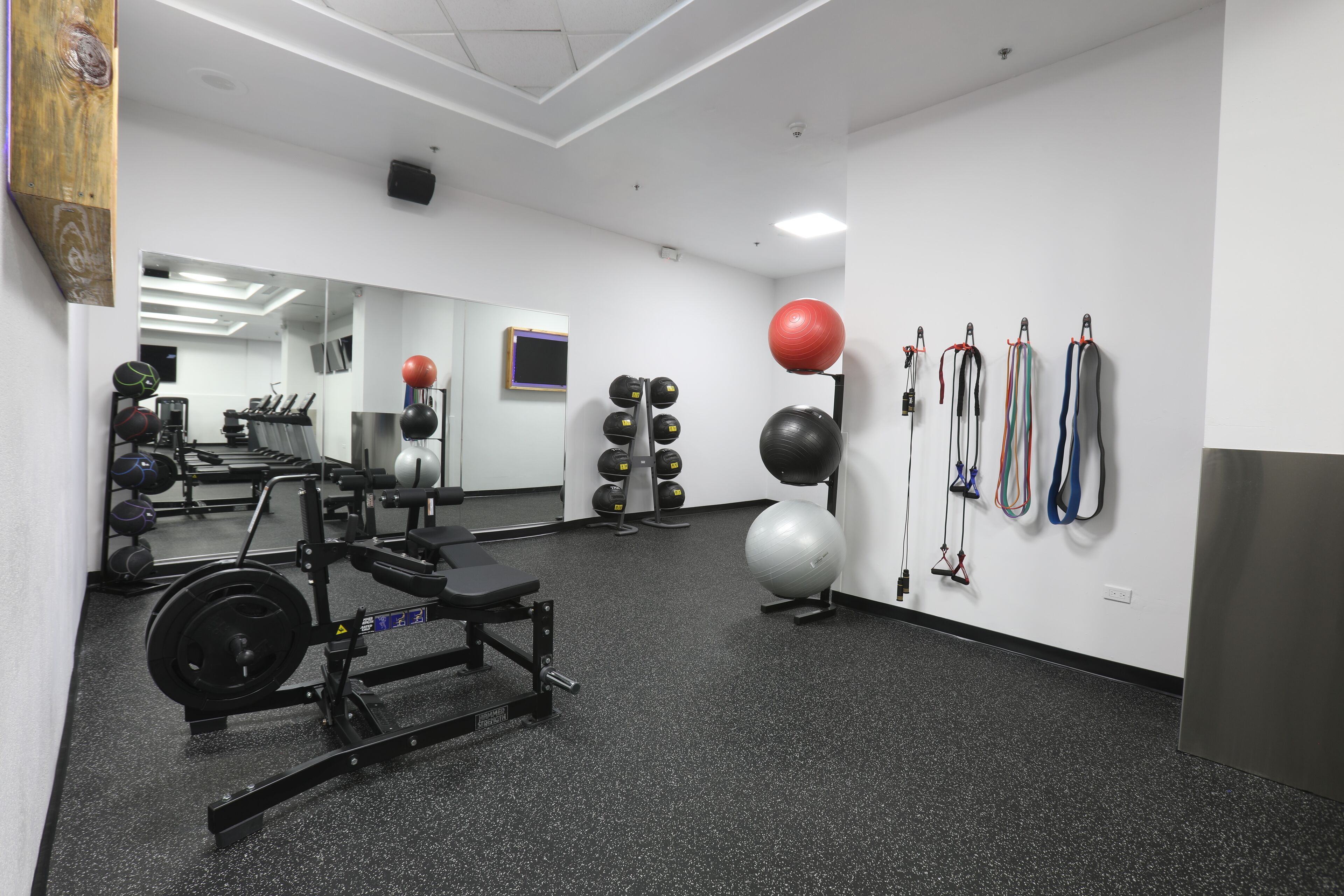 A gym with exercise equipment, a mirror, and various fitness balls.