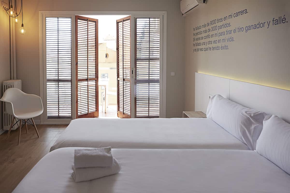 Une chambre d’hôtel avec deux lits, une chaise et un mur orné de texte.
