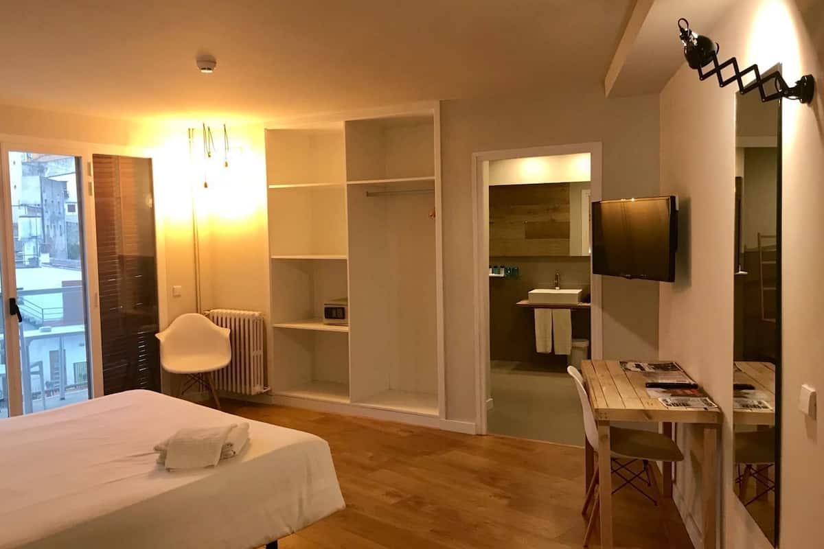Une chambre d’hôtel comprenant un lit, un bureau, une chaise, une télévision, une armoire et une salle de bain.