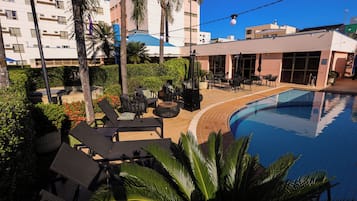 Una piscina al aire libre, sombrillas, sillones reclinables de piscina