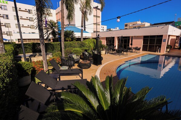 Una piscina al aire libre, sombrillas, sillones reclinables de piscina