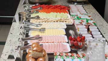 A buffet with various food items including fruits, cheeses, and pastries.