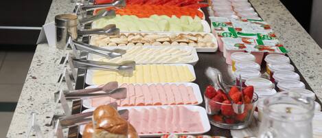 Un bufé con diversos alimentos, como frutas, quesos y pasteles.