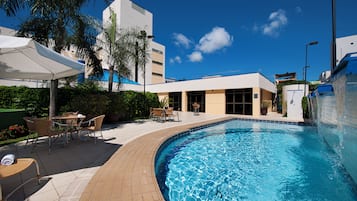 Una piscina al aire libre, sombrillas, sillones reclinables de piscina
