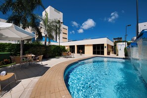 Una piscina al aire libre, sombrillas, sillones reclinables de piscina