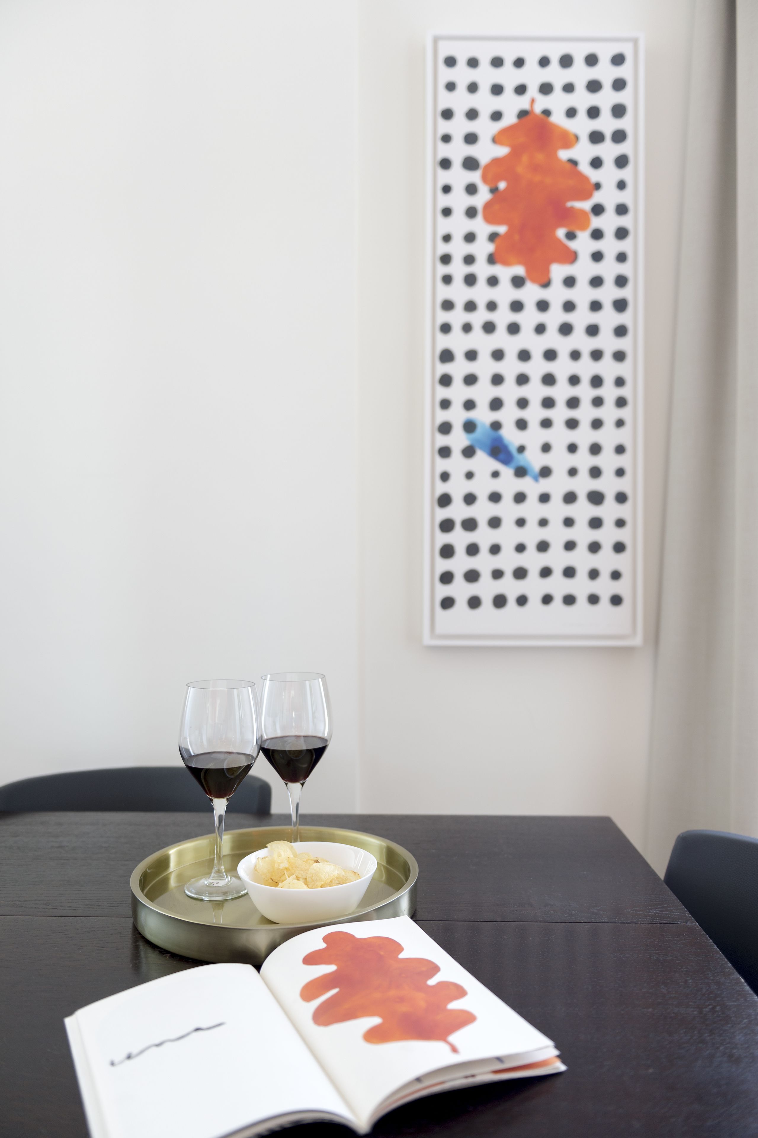 A dining table with two wine glasses, a bowl of chips, and a book.