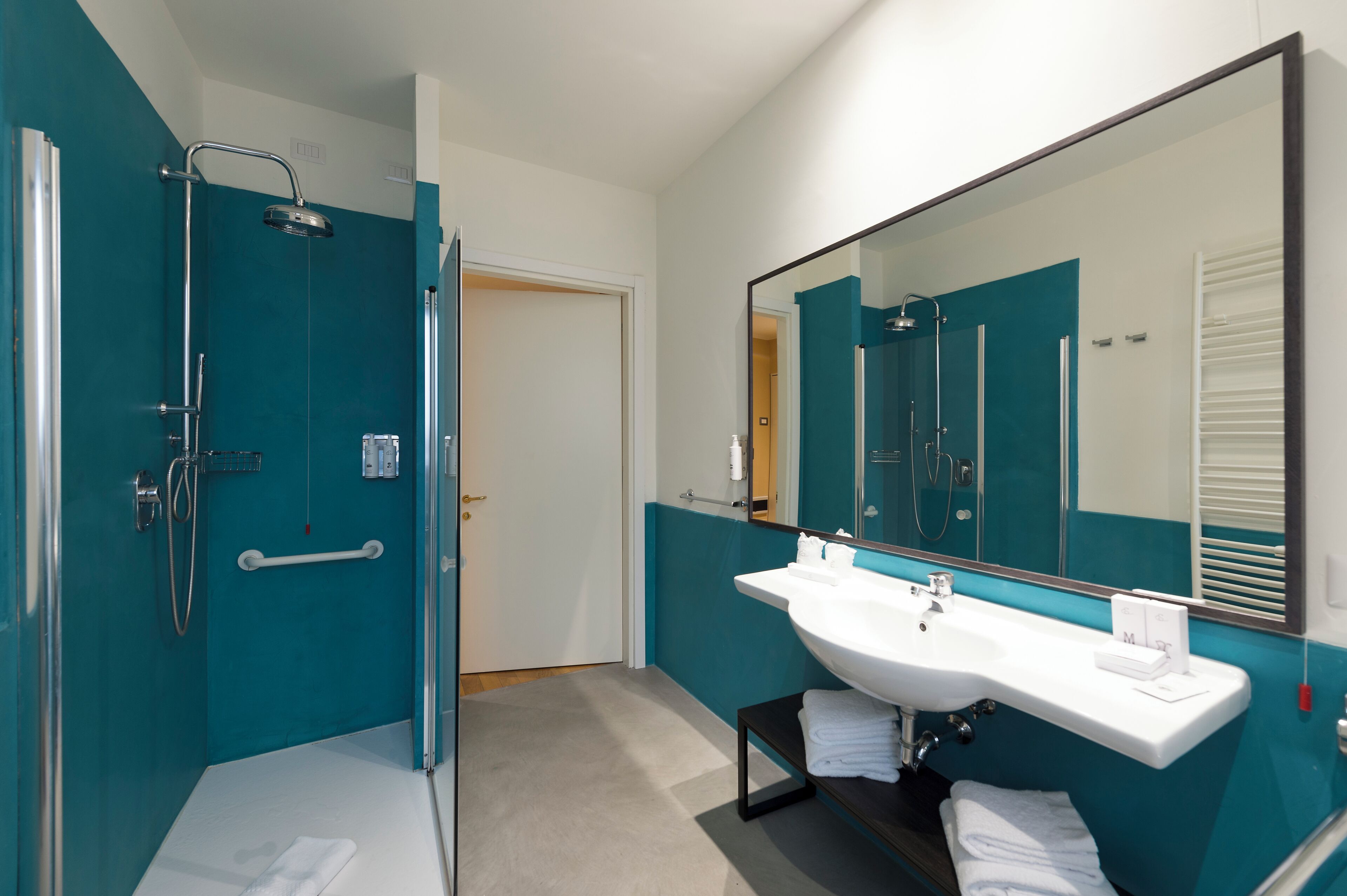 A modern bathroom with a large mirror, a white sink, and a shower area.