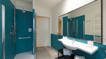 A modern bathroom with a large mirror, a white sink, and a shower area.