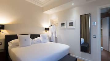 Una habitación de hotel con una cama grande, mesitas de noche, un espejo y un armario.