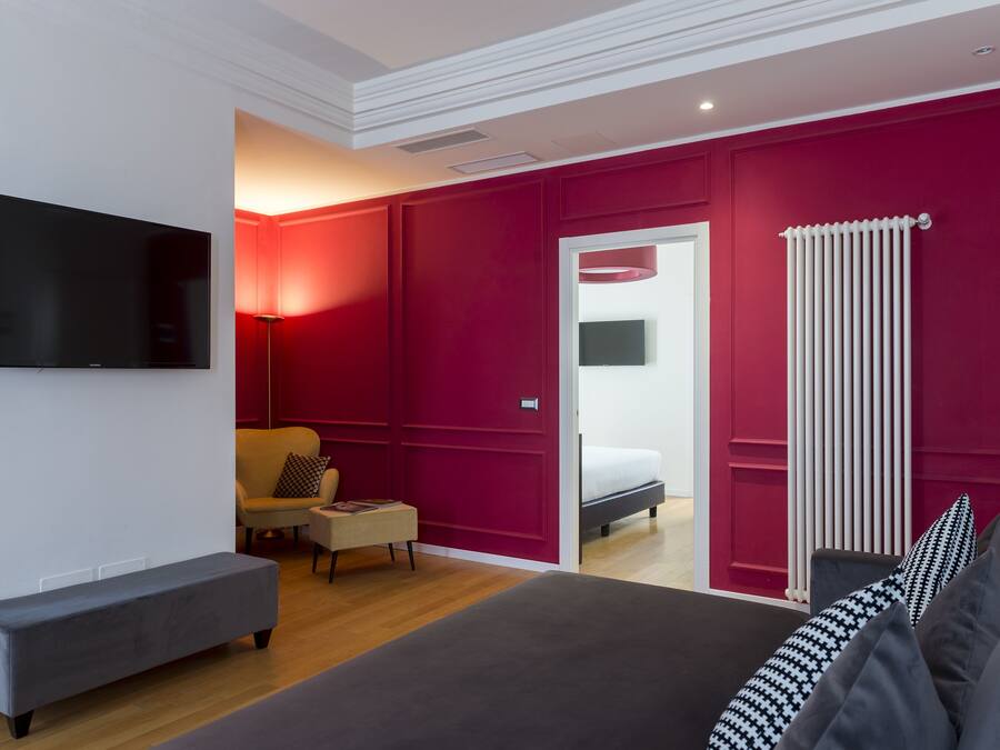Un dormitorio moderno con una cama grande, un televisor de pantalla plana, un sofá y una silla.