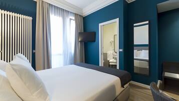 Camera d'albergo con un letto grande, una TV a muro, uno specchio e vista sul bagno.