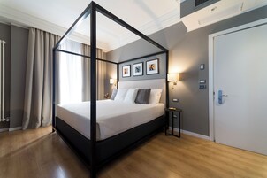 Un dormitorio moderno con una cama con dosel, una mesita de noche, una puerta y cuadros en la pared.